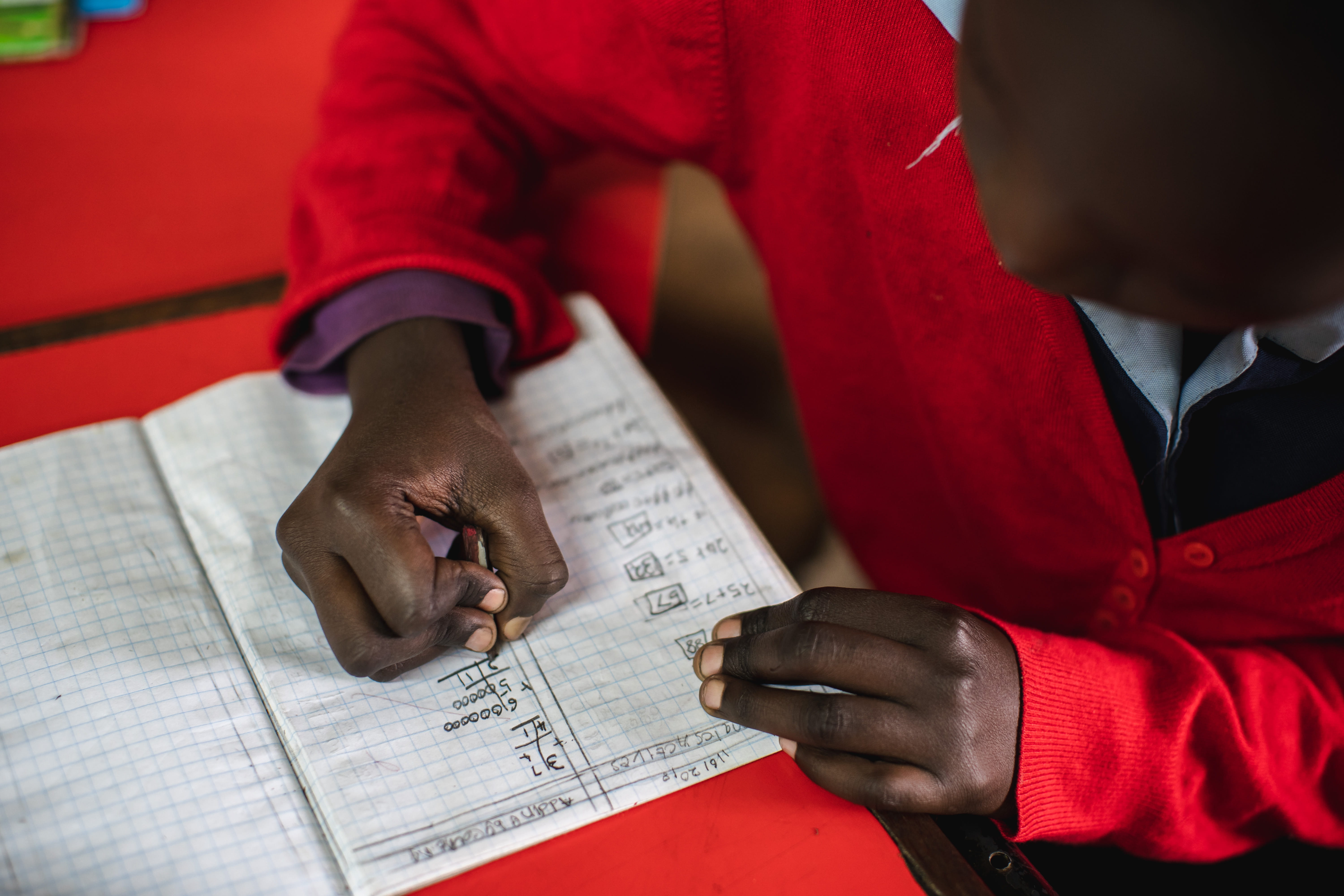 Junge ist über ein Heft gebeugt und schreibt darin. (Quelle: Kindernothilfe)