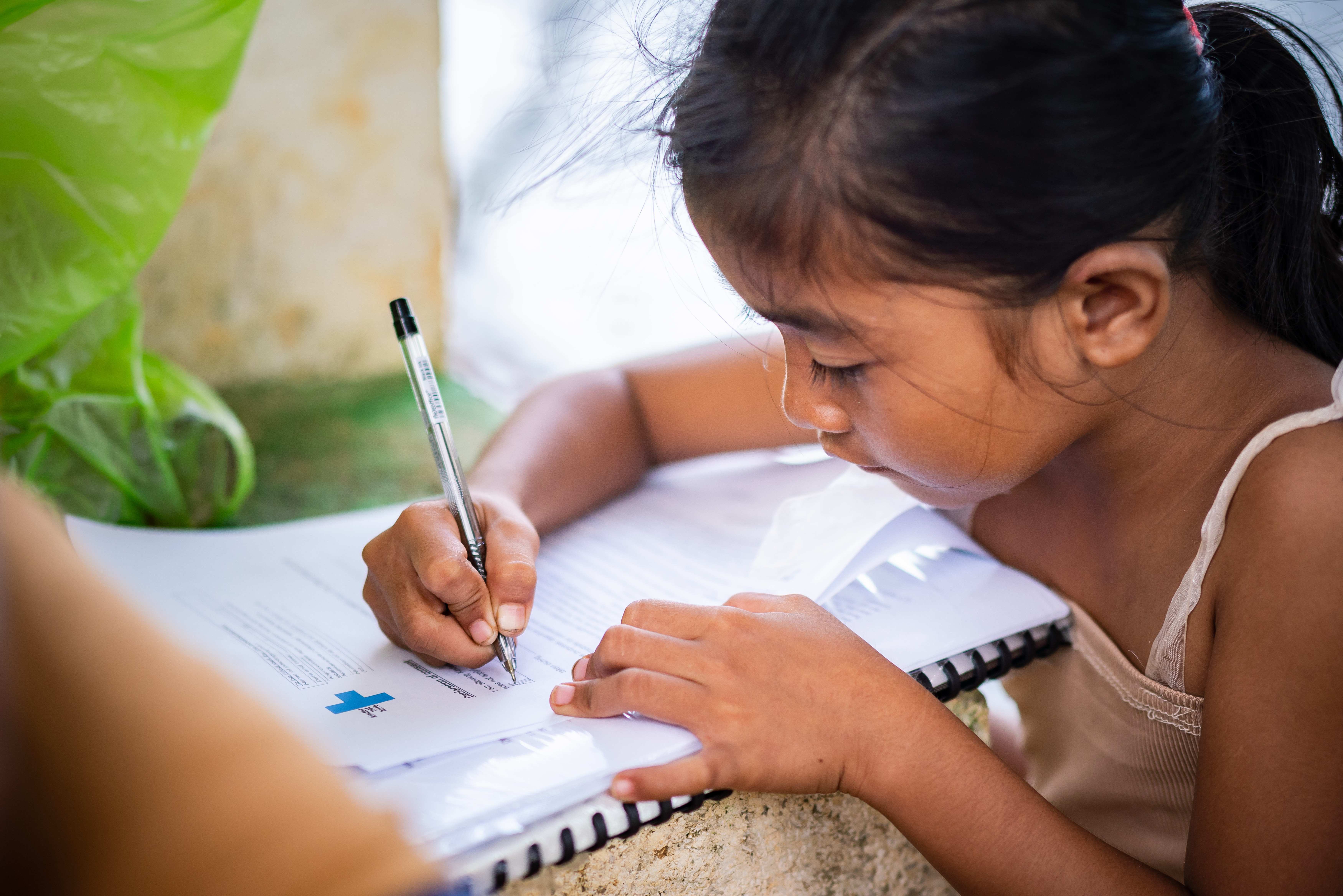Una niña de escuela escribe en un cuaderno