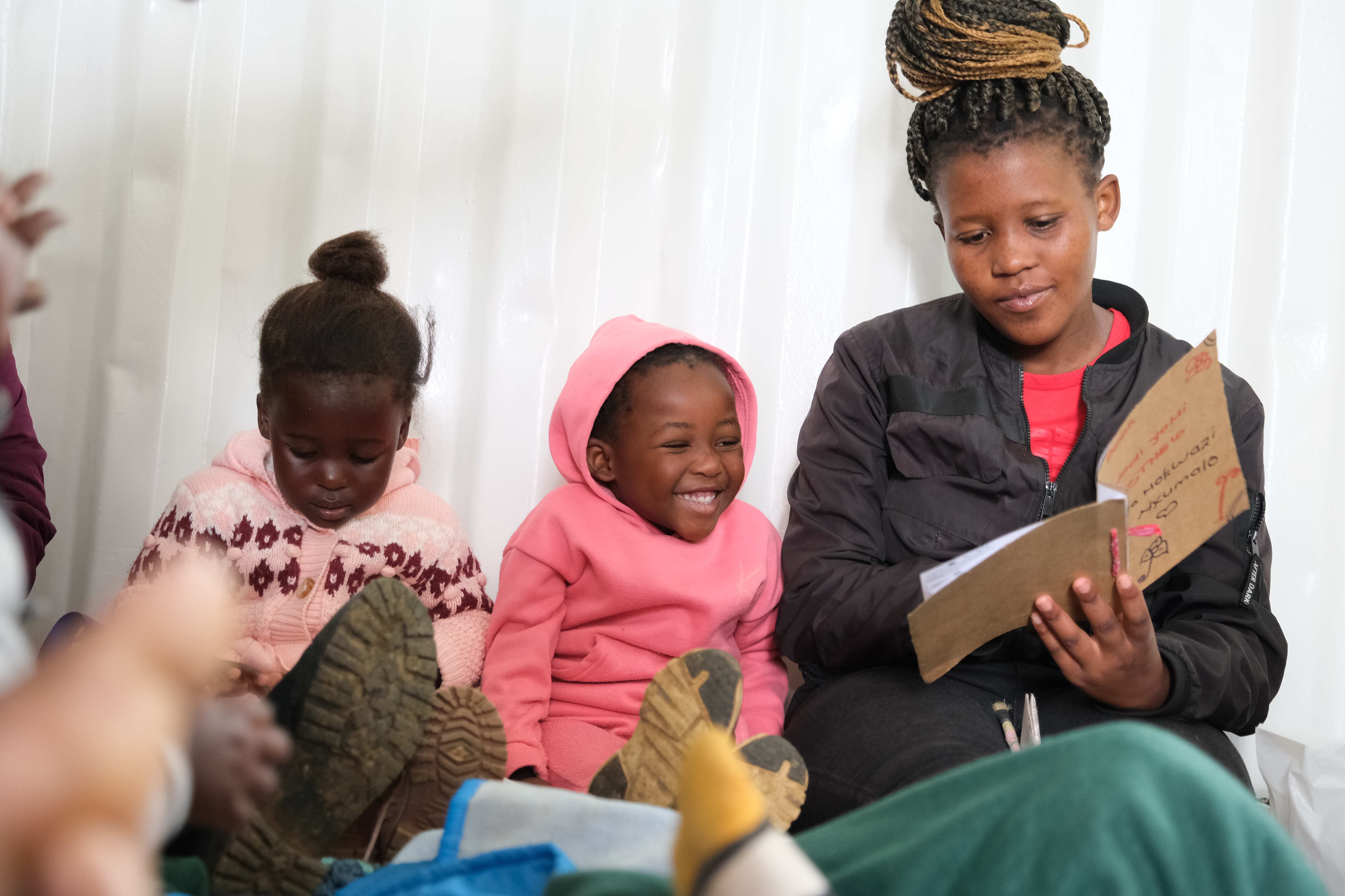 In the early childhood development project (edp), a care giver reads to two toddlers (source: Malte Pfau)