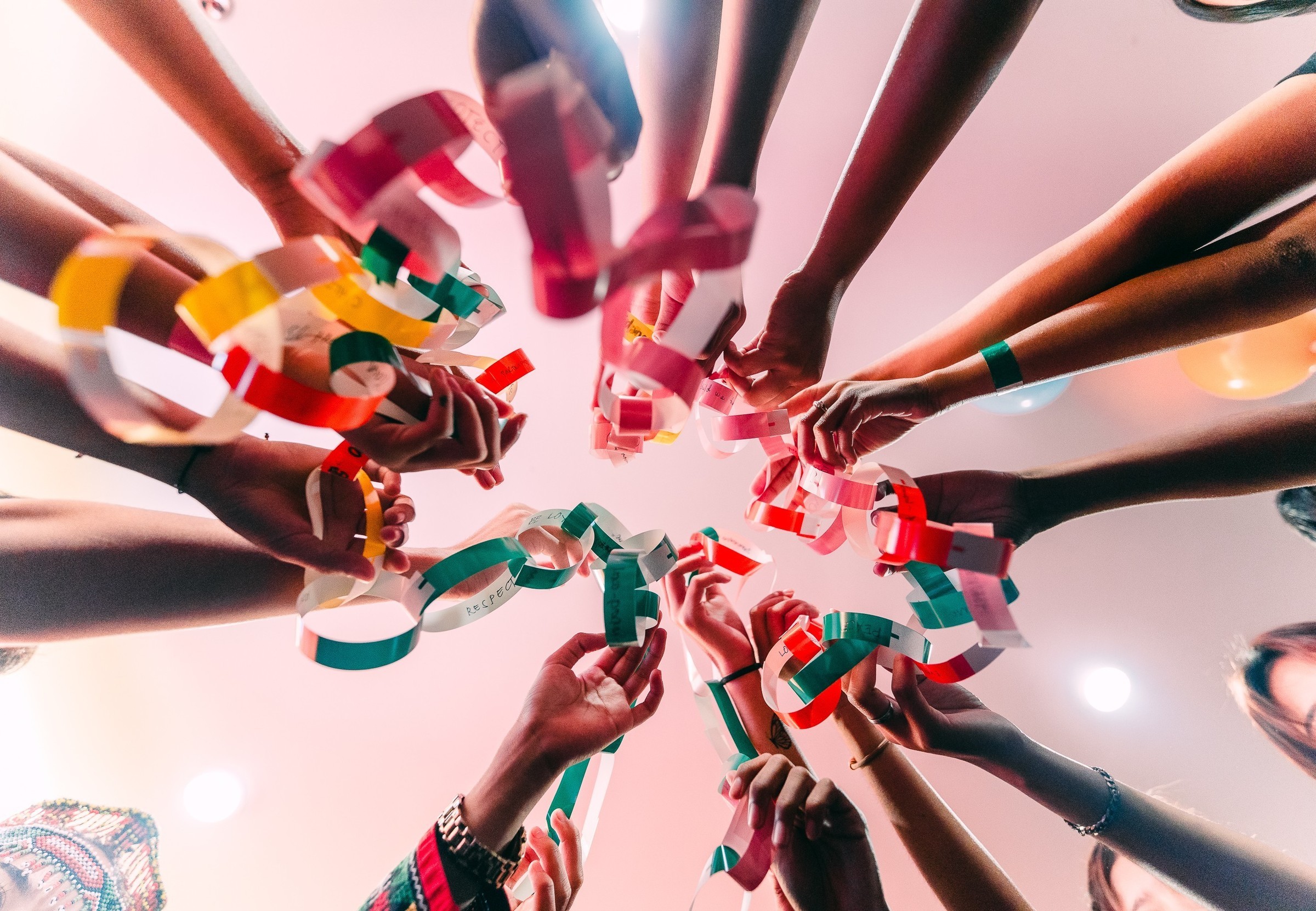 A circle of hands holds a colourful paper chain with statements (Source: Kindernothilfe-Partner)