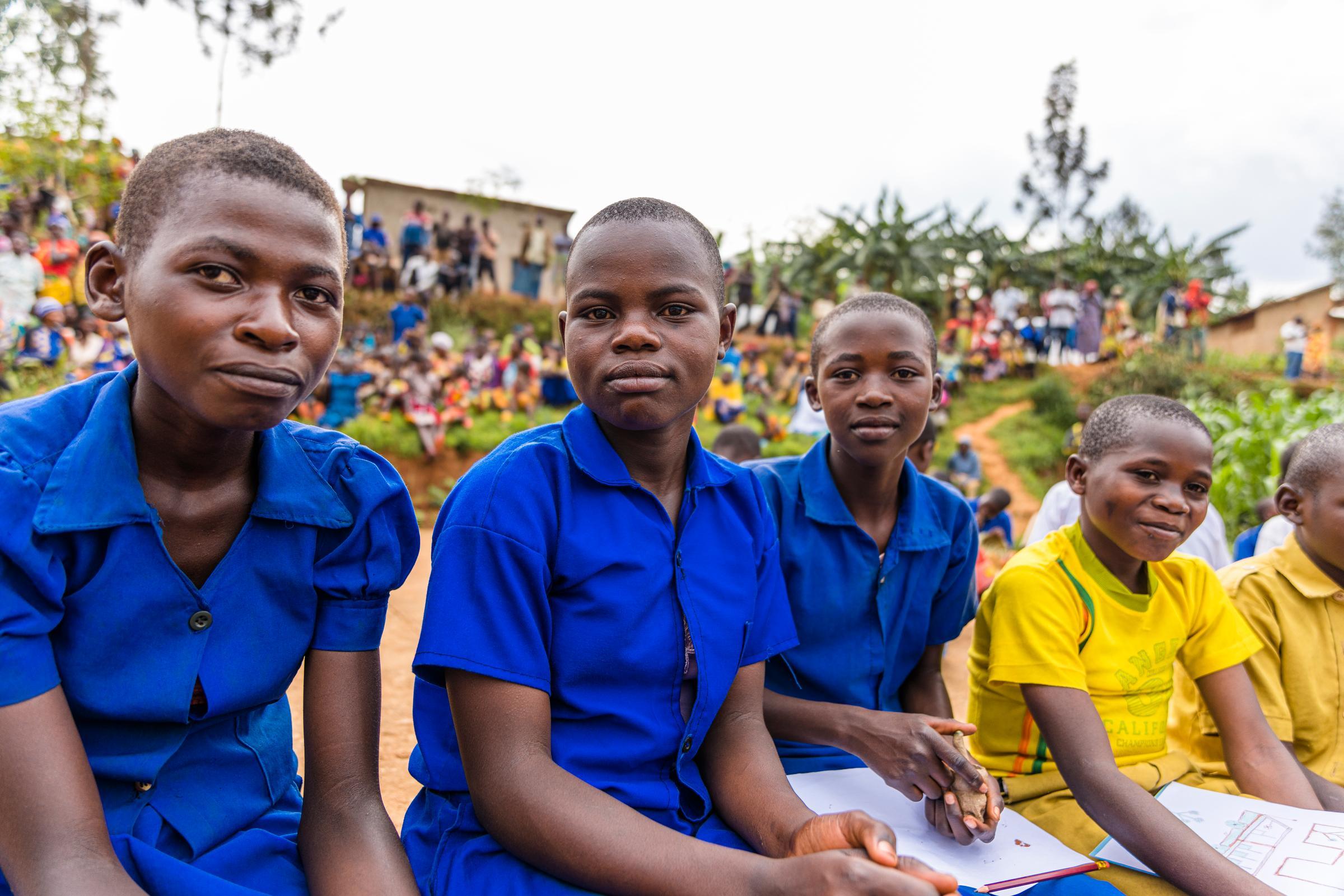 Children in blue and yellow shirts sit next to each other (Source: Martin Bondzio)