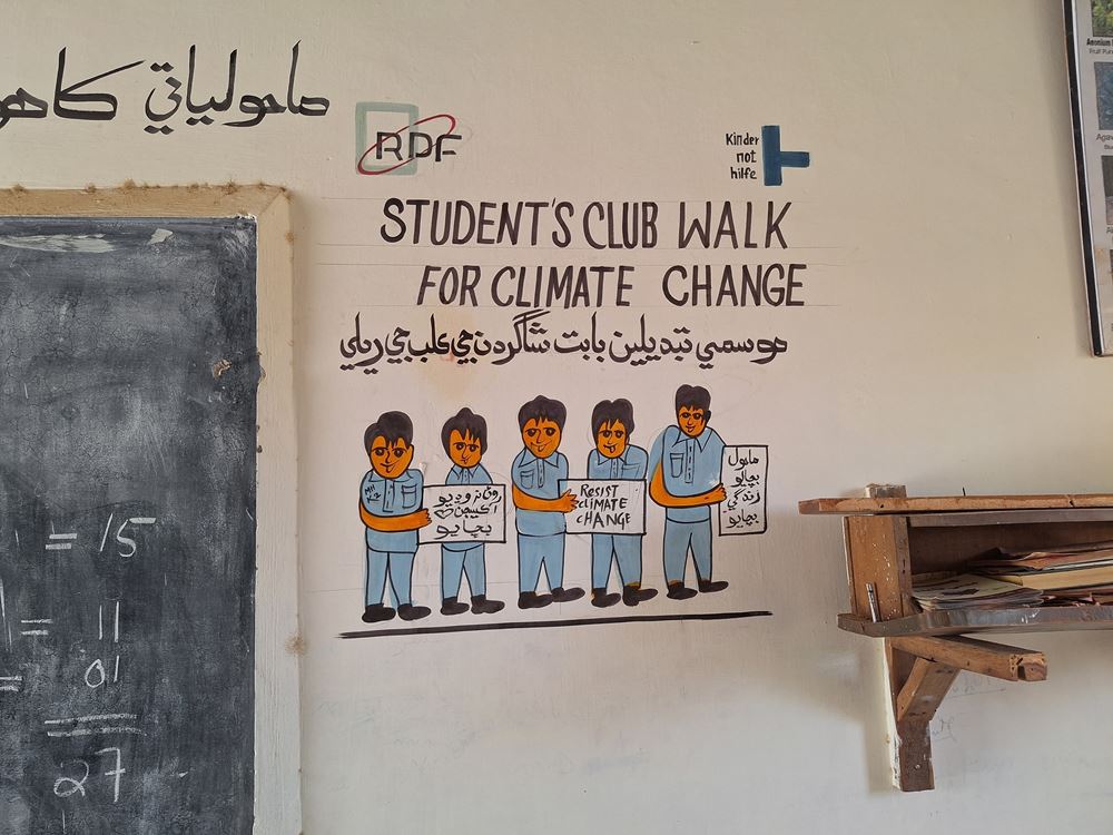 Mural "Student's club walk for climate change" next to a black board (Source: Kindernothilfe partner organisation GLOW)
